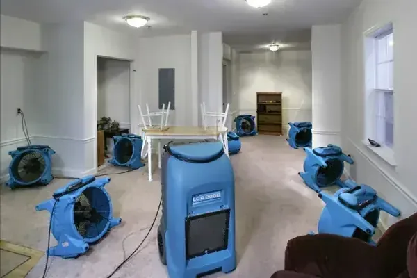 Air movers and a dehumidifier set up in a water-damaged room