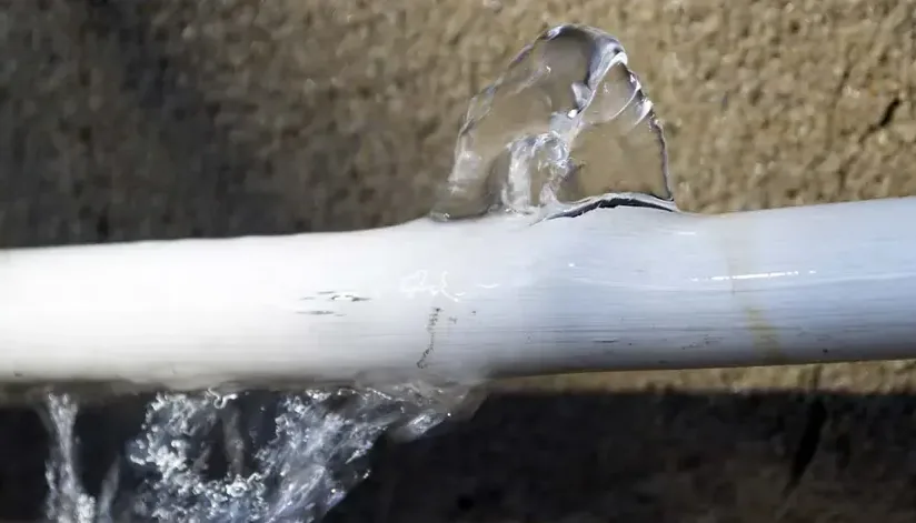 Water spraying from a split plastic pipe