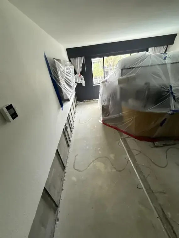 Hallway wall opened at the base behind plastic containment