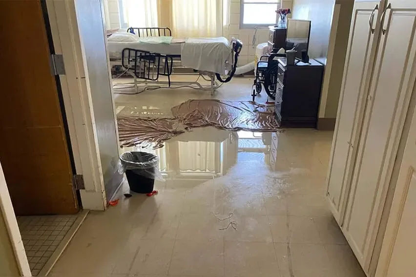 Water and sediment across an interior floor beyond an open doorway