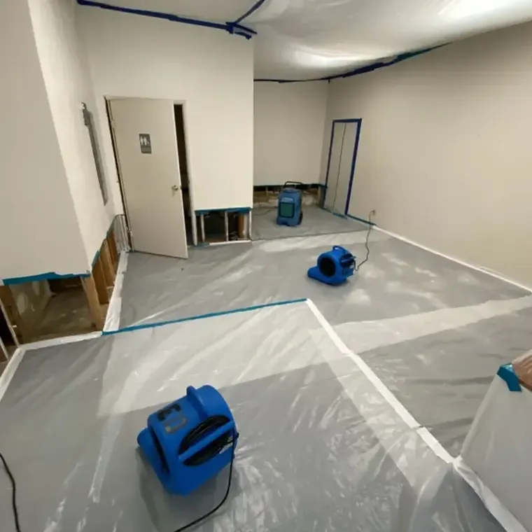 Blue air movers on protective floor sheeting inside a contained room
