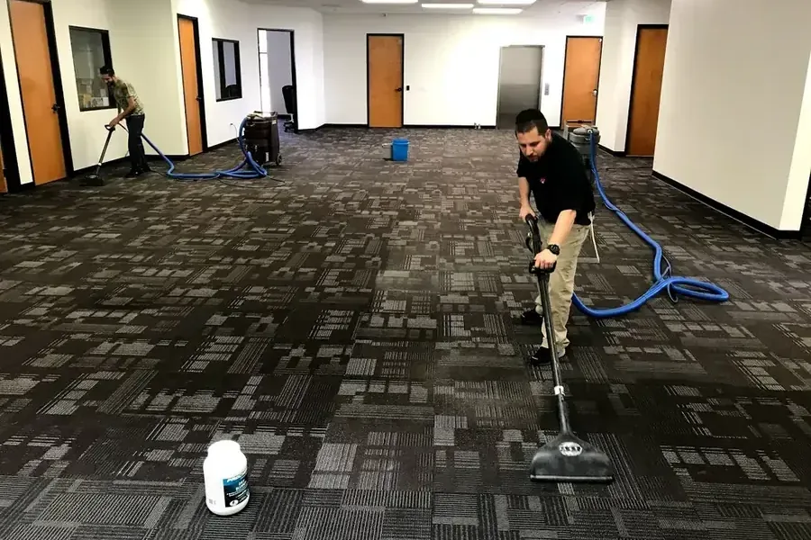 Technicians using extraction wands on carpet inside a commercial room