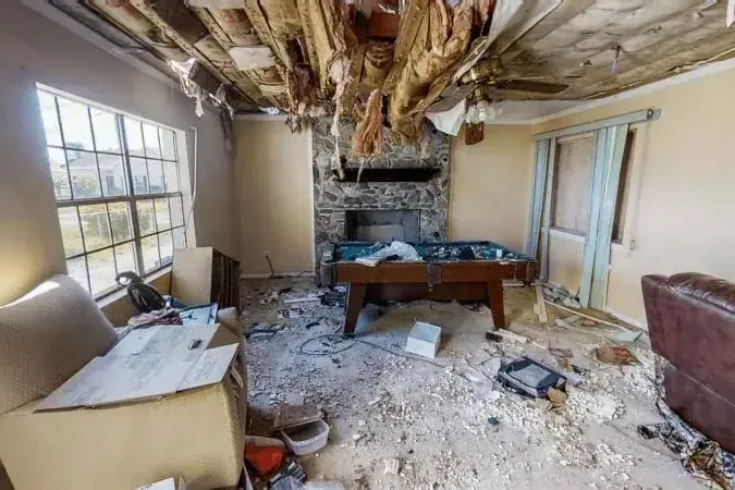 Exposed ceiling insulation and fallen debris inside a damaged room