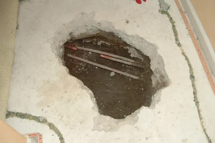Opened concrete floor revealing copper supply pipes
